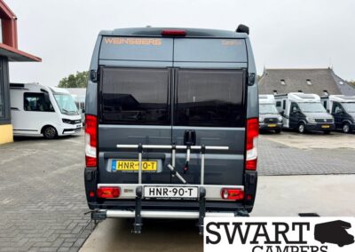 Rear view of a gray Weinsberg CaraBus camper van with bike rack and Dutch license plate HNR-90-T on a parking lot; Swart Campers watermark visible at bottom right.